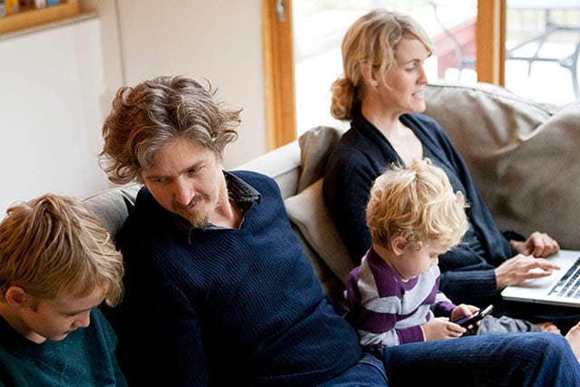 Familie sidder sammen i sofaen.