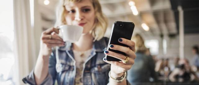 Kvinde sidder med sin mobil. Få overblik over dine transaktioner med re:member appen.