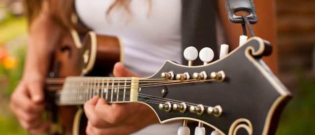 Kvinde spiller guitar. Se eller vælg in PIN-kode i re:member netbank.
